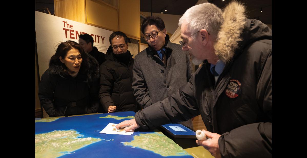 Photo by Ariana Crockett O'Harra GOLD – Nome Mayor Kenny Hughes shows off placer gold to Mayor Heong-Joon Park of Busan, South Korea and other representatives from Busan as they visited the Carrie M.McLain Museum on Tuesday, January 6.